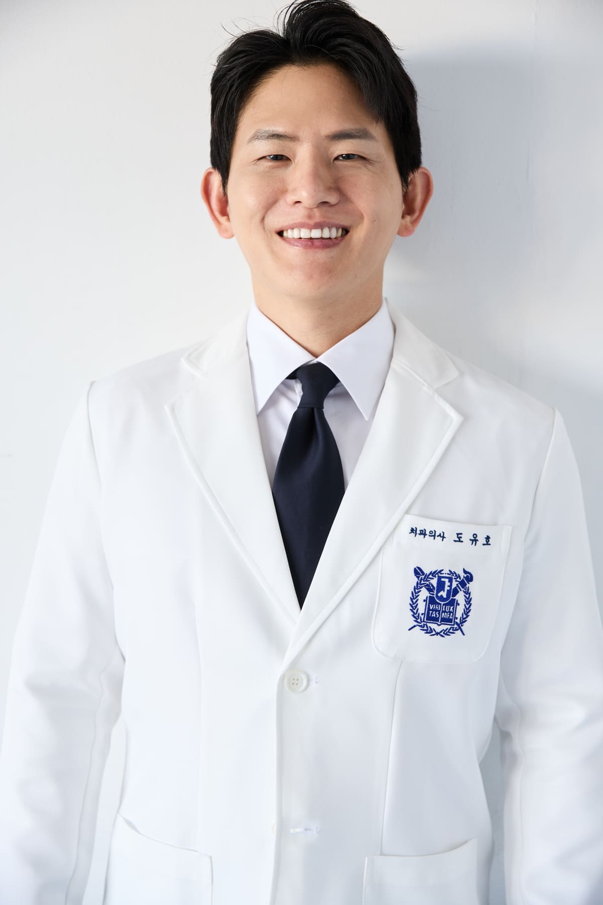 Dr. Yuho Doh, clinical director of Seoul Today Dental Clinic, in a white coat with the Seoul National University crest