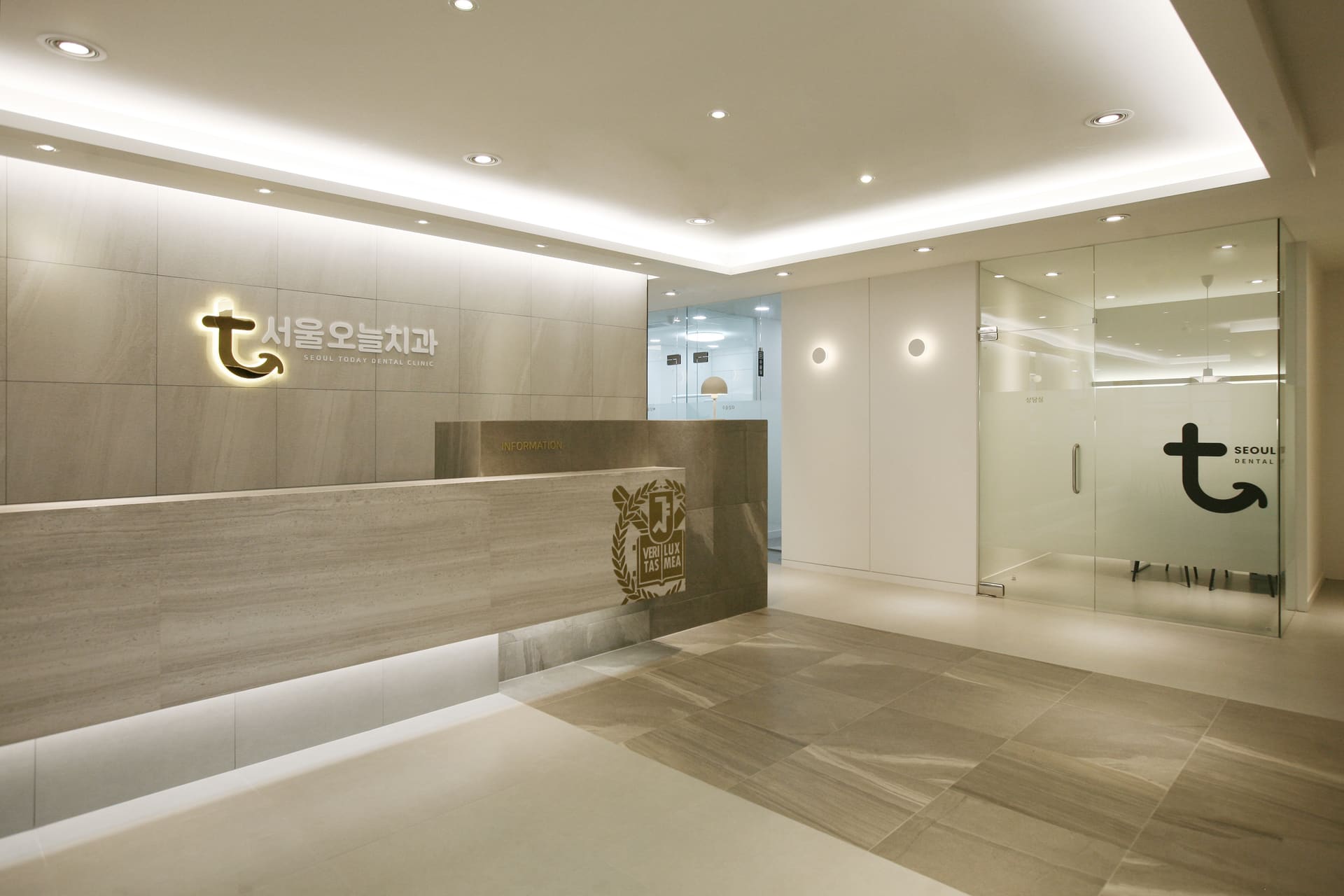Reception of Seoul Today Dental Clinic with a backlit logo wall, stone information desk, and the Seoul National University crest